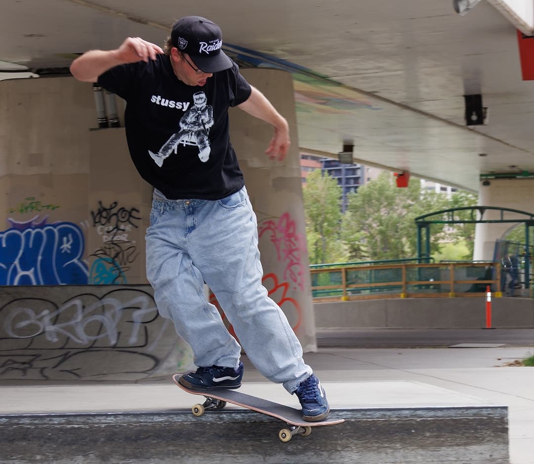 Michael doing a back smith grind on a concrete ledge under a bridge in Calgary